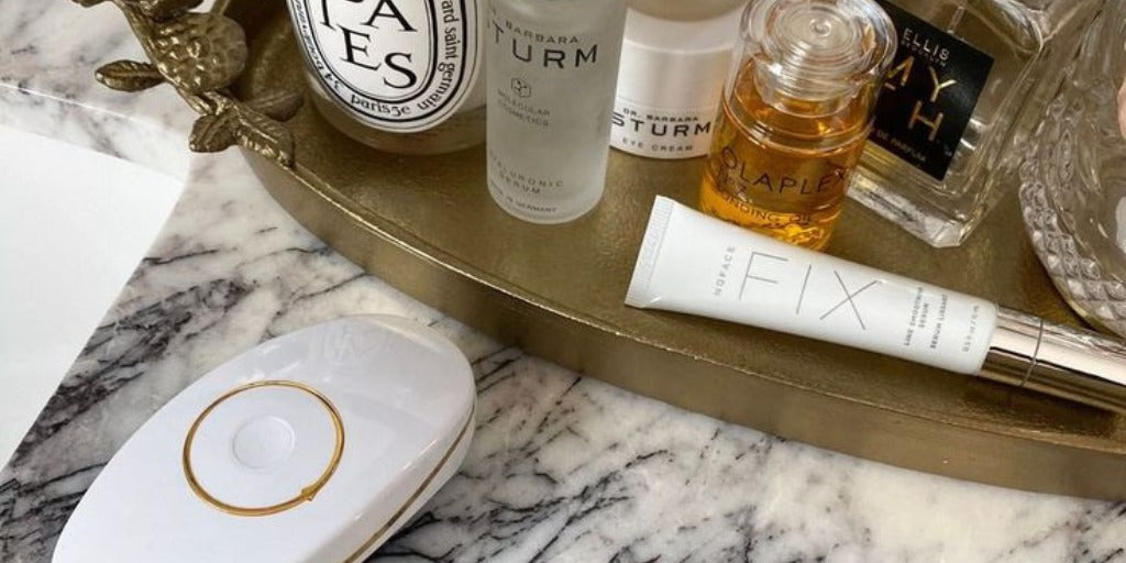 ZIIP GX resting on a marble counter beside a gold tray of skincare and beauty products.