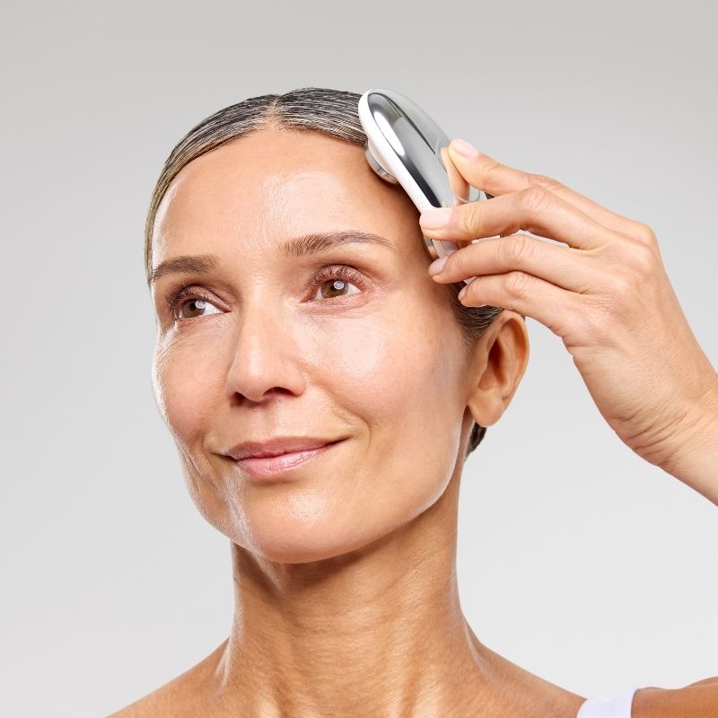 Woman using the ZIIP HALO Microcurrent device on her face