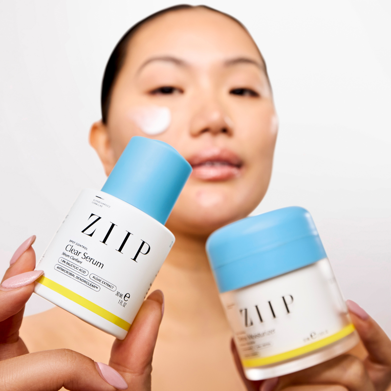 Woman holding ZIIP Clear serum and Detox moisturiser bundle with product applied to cheek